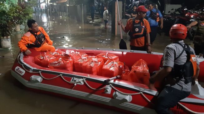 Petugas BPBD Tangsel membawa nasi boks untuk dibagikan kepada warga Kampung Bulak, Kelurahan Pondok Kacang Timur, Pondok Aren, yang terdampak banjir, Kamis (17/3/2022) malam. [Dok. BPBD Tangerang Selatan]