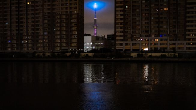 Pemandangan Tokyo Skytree di antara area perumahan yang gelap gulita karena pemadaman listrik setelah gempa berkekuatan 7,3 SR mengguncang wilayah Jepang Timur di Tokyo, Jepang, Kamis (17/3/2022). [Philip FONG / AFP]