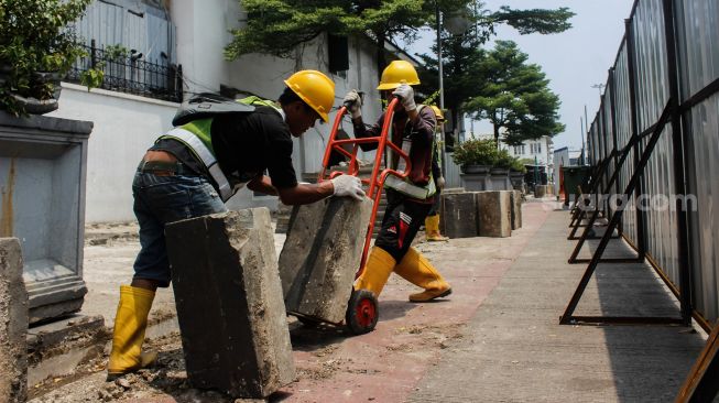 Pekerja membongkar jalur pedestrian di Kawasan Kota Tua, Jakarta, Kamis (17/3/2022). [Suara.com/Septian]