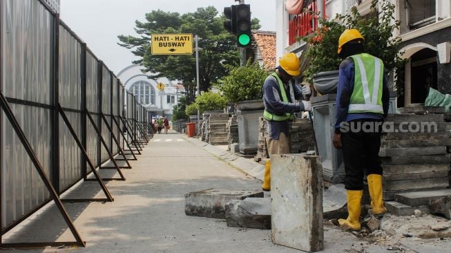 Pekerja membongkar jalur pedestrian di Kawasan Kota Tua, Jakarta, Kamis (17/3/2022). [Suara.com/Septian]