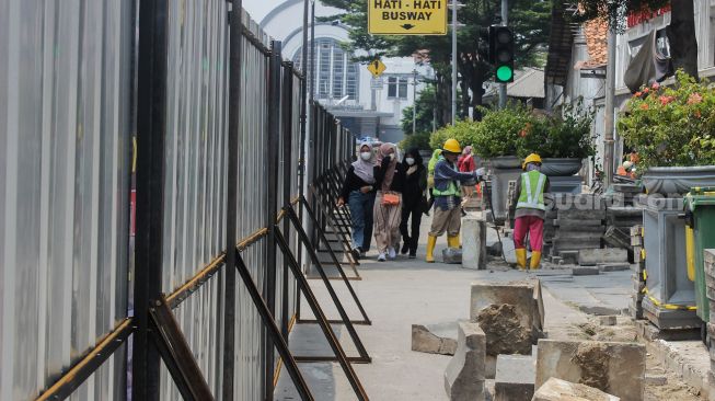 Pekerja membongkar jalur pedestrian di Kawasan Kota Tua, Jakarta, Kamis (17/3/2022). [Suara.com/Septian]