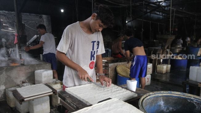 Pekerja memproduksi tahu dan tempe berbahan dasar kedelai di kawasan Duren Tiga Raya, Jakarta selatan, Jumat (18/3/2022). [Suara.com/Alfian Winanto]