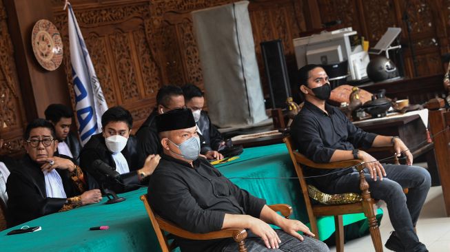 Terdakwa unlawful killing anggota Laskar FPI Briptu Fikri Ramadhan (kanan) dan Ipda M Yusmin Ohorella ((kedua kanan) didampingi Koordinator Tim Penasihat Hukum Henry Yosodiningrat (kiri) mengukuti sidang putusan yang digelar secara virtual di Jakarta, Jumat (18/3/2022)