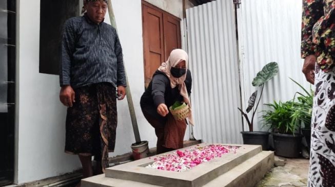 Seorang warga menabur bunga di sekitar Makam Mbah Dalang di Kampung Sosrokusuman, Kelurahan Suryatmajan, Kemantren Danurejan, Kota Jogja, Sabtu (18/3/2022). [Muhammad Ilham Baktora / SuaraJogja.id]