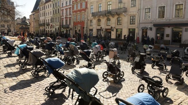 Ratusan kereta dan keranjang bayi kosong di pajang di luar gedung dewan kota di Lviv, Ukraina, Jumat (18/3/2022). [Yuriy Dyachyshyn / AFP]
