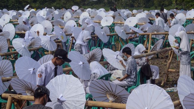 Sejumlah siswa melukis payung geulis pada Festival, Lomba dan Rekor Melukis 2022 Payung Geulis Se-Jawa Barat di SMA Negeri 10 Kota Tasikmalaya, Jawa Barat, Sabtu (19/3/2022). [ANTARA FOTO/Adeng Bustomi/rwa]