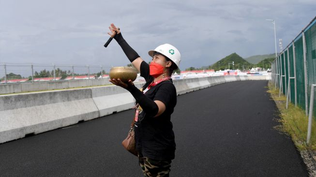 Seorang wanita melakukan ritual tradisional agar cuaca cerah saat sesi latihan MotoGP Mnadalika 2022 di Sirkuit Internasional Mandalika, Lombok Tengah, Jumat (18/3/2022). [SONNY TUMBELAKA / AFP]