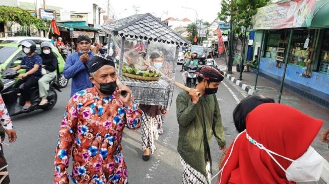 Sejumlah warga mengarak ingkung dan tumpeng dalam prosesi Upacara Nyadran Punggawa Raja menjelang bulan suci Ramadan di sepanjang Jalan Mataram, Kelurahan Suryatmajan, Kemantren Danurejan, Kota Jogja, Sabtu (18/3/2022). [Muhammad Ilham Baktora / SuaraJogja.id]