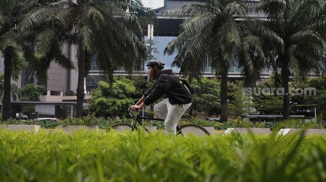 Pesepeda melintasi jalur khusus sepeda di Jalan Jenderal Sudirman, Jakarta, Minggu (20/3/2022). [Suara.com/Angga Budhiyanto]