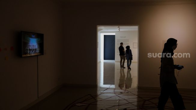 Pengunjung mengamati karya seni dalam pameran tunggal karya Otty Widasary yang bertajuk "Partisan" di Gedung D, Galeri Nasional, Jakarta, Minggu (20/3/2022). [Suara.com/Angga Budhiyanto]