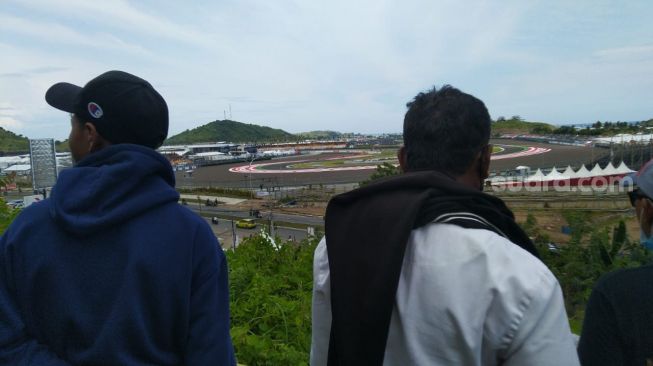 Warga lokal nonton MotoGP Mandalika 2022 di atas Bukit Rangkap yang terletak di utara Sirkuit Mandalika, Minggu (20/3/2022). [Arief Apriadi/Suara.com]
