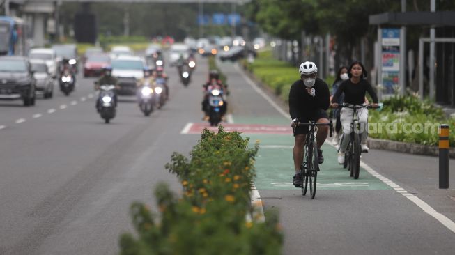 Pesepeda melintasi jalur khusus sepeda di Jalan Jenderal Sudirman, Jakarta, Minggu (20/3/2022). [Suara.com/Angga Budhiyanto]