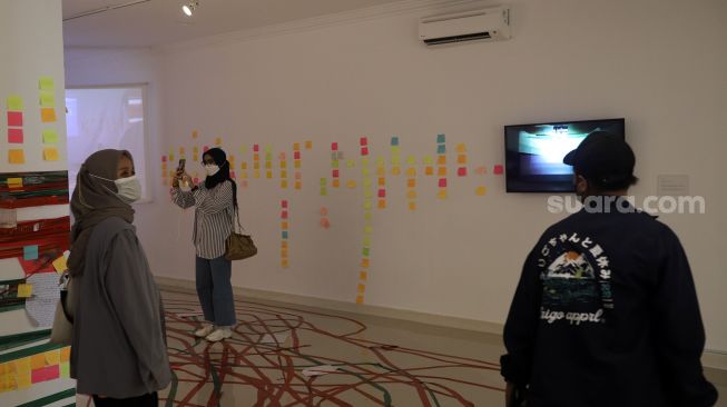 Pengunjung mengamati karya seni dalam pameran tunggal karya Otty Widasary yang bertajuk "Partisan" di Gedung D, Galeri Nasional, Jakarta, Minggu (20/3/2022). [Suara.com/Angga Budhiyanto]