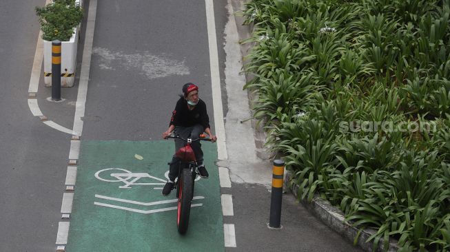 Pesepeda melintasi jalur khusus sepeda di Jalan Jenderal Sudirman, Jakarta, Minggu (20/3/2022). [Suara.com/Angga Budhiyanto]