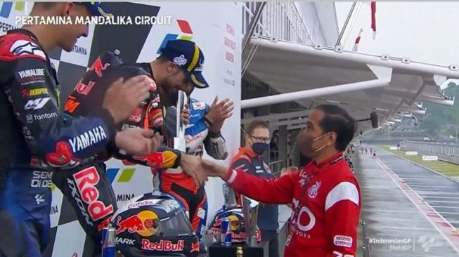 Tangkapan layar - Presiden Joko Widodo (kanan) menyalami pebalap tim Red Bull KTM asal Portugal Miguel Oliveira seusai menyerahkan trofi juara seri kedua MotoGP 2022 Grand Prix Indonesia di Sirkuit Pertamina Mandalika, Lombok Tengah, Nusa Tenggara Barat, Minggu (20/3/2022). (ANTARA/Gilang Galiartha)