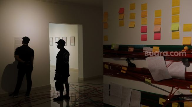 Pengunjung mengamati karya seni dalam pameran tunggal karya Otty Widasary yang bertajuk "Partisan" di Gedung D, Galeri Nasional, Jakarta, Minggu (20/3/2022). [Suara.com/Angga Budhiyanto]