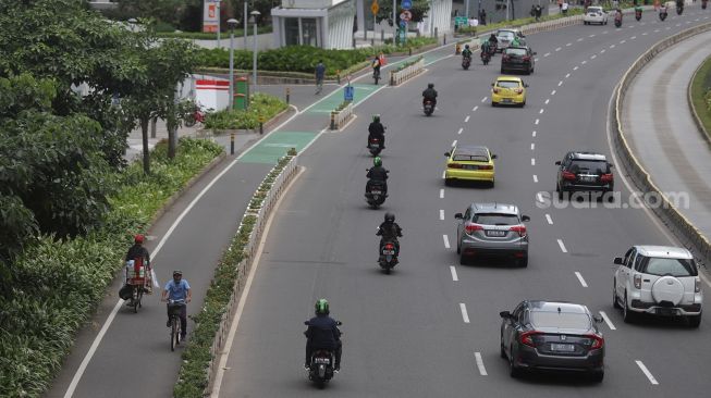 Pesepeda melintasi jalur khusus sepeda di Jalan Jenderal Sudirman, Jakarta, Minggu (20/3/2022). [Suara.com/Angga Budhiyanto]