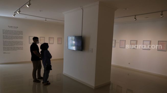 Pengunjung mengamati karya seni instalasi video dalam pameran tunggal karya Otty Widasary yang bertajuk "Partisan" di Gedung D, Galeri Nasional, Jakarta, Minggu (20/3/2022). [Suara.com/Angga Budhiyanto]