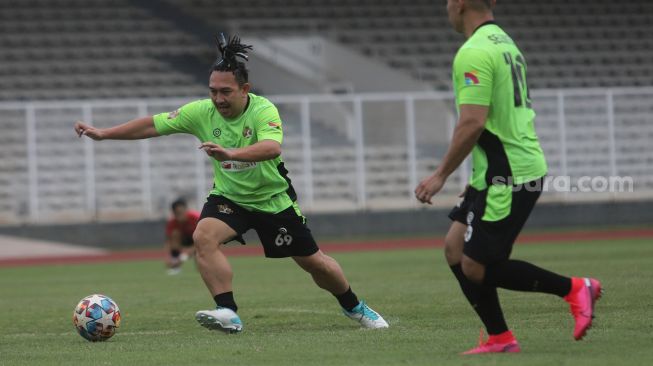 Aktor Augie Fantinus menggiring bola saat bermain sepakbola bersama Selebritis FC di Stadion Madya, Kompleks Gelora Bung Karno, Jakarta, Senin (21/3/2022). [Suara.com/Angga Budhiyanto]