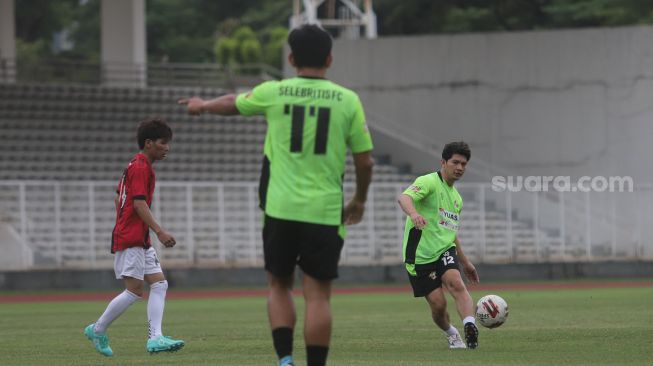 Aktor Iko Uwais memberikan umpan saat bermain sepakbola bersama Selebritis FC di Stadion Madya, Kompleks Gelora Bung Karno, Jakarta, Senin (21/3/2022). [Suara.com/Angga Budhiyanto]