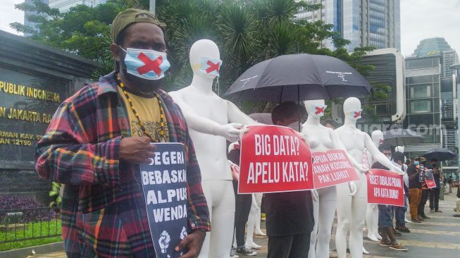 Sejumlah aktivis mengenakan masker bertanda silang melakukan aksi di depan Polda Metro Jaya, Jakarta Selatan, Senin (21/3/2022). [Suara.com/Alfian Winanro]