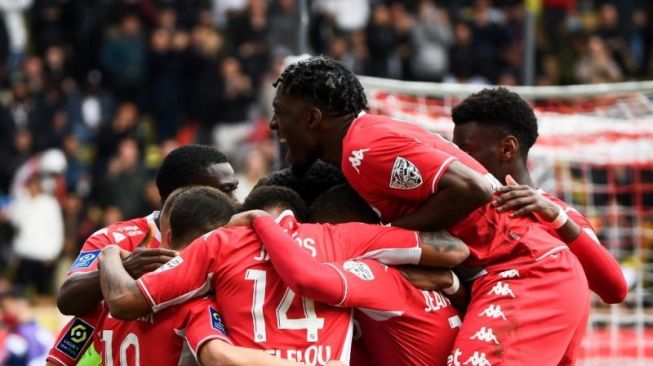 Pemain Monaco Wissam Ben Yedder dikerubuti rekan-rekan satu timnya setelah memasukkan gol dari tendangan penalti yang menuntaskan kemenangan 3-0 Monaco atas Paris Saint Germain (PSG) di Louis II Stadium (Stade Louis II) di Monako, 20 Maret  2022. (AFP/CLEMENT MAHOUDEAU)