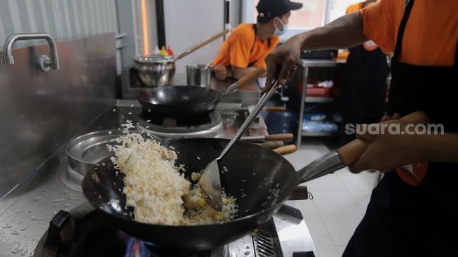 Juru masak membuat nasi goreng pesanan pelanggan di salah satu gerai di kawasan Ampera, Jakarta, Senin (21/3/2022). [Suara.com/Angga Budhiyanto]