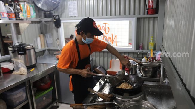 Juru masak membuat nasi goreng pesanan pelanggan di salah satu gerai di kawasan Ampera, Jakarta, Senin (21/3/2022). [Suara.com/Angga Budhiyanto]