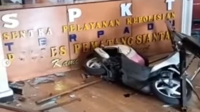 Kondisi motor dan ruang SPKT Polres Pematangsiantar pasca ditabrak pengendara motor wanita berhijab, Senin (21/3/2022). [Instagram@terangmedia]