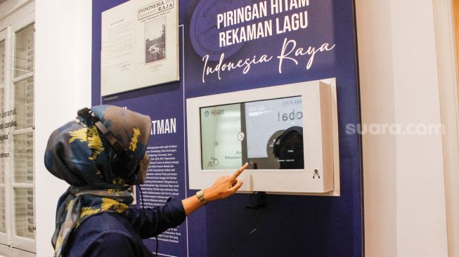 Pengunjung mendengar piringan hitam rekaman lagu Indonesia Raya di Museum Sumpah Pemuda, Senen, Jakarta Pusat, Selasa (22/3/2022). [Suara.com/Alfian Winanto]