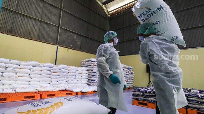 Pekerja mengoperasikan mesin Rice To Rice (RTR) untuk mengisi karung beras medium di Gudang RTT Bulog, Kelapa Gading, Jakarta Utara, Rabu (23/3/2022). [Suara.com/Alfian Winanto]