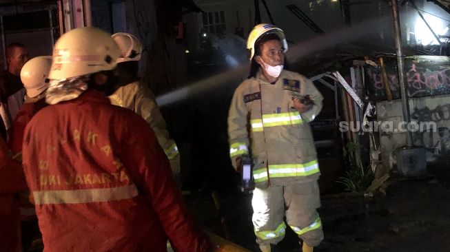 Petugas damkar sedang melakukan pendinginan kebakaran di Kemanggisan, Jakarta Barat, Kamis (24/3/2022) malam. [Suara.com/Faqih Fathurrahman]