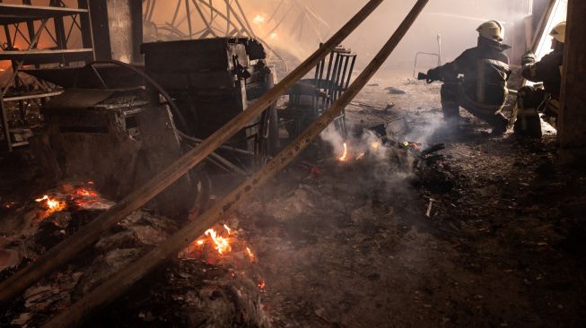 Petugas pemadam kebakaran memadamkan api di gudang yang terbakar akibat dihantam rudal Rusia di pinggiran kota Kyiv, Ukraina, kamis (24/3/2022). [FADEL SENNA / AFP]