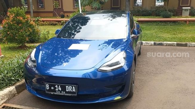 Bareskrim Porli memamerkan mobil Tesla Indra Kenz jelang konferensi pers kasus afiliator tersebut, Jumat (25/3/2022). [Adiyoga Priyambodo/Suara.com]