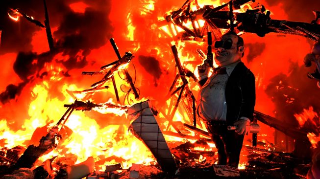 Boneka-boneka dari karton yang biasa disebut 'Ninot' dan 'Falla' dibakar saat Festival Fallas di Valencia, Spanyol, Sabtu (19/3/2022). [Jose Jordan / AFP] 