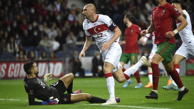 PPemain depan Turki Burak Yilmaz (tengah) melakukan selebrasi usai mencetak gol saat pertandingan sepak bola play-off kualifikasi Piala Dunia 2022 antara Portugal dan Turki di stadion Dragao, Porto, Portugal, Kamis (24/3/2022). [MIGUEL RIOPA / AFP]