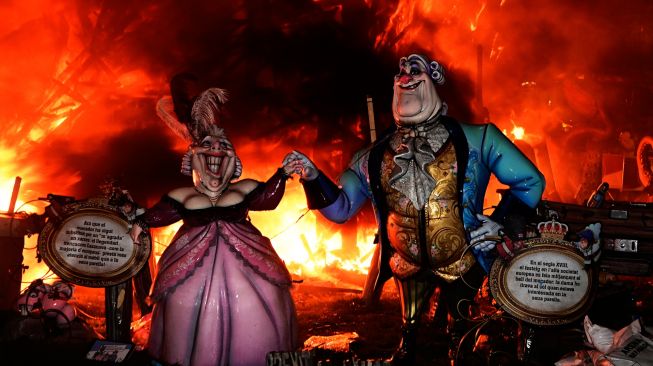 Boneka-boneka dari karton yang biasa disebut 'Ninot' dan 'Falla' dibakar saat Festival Fallas di Valencia, Spanyol, Sabtu (19/3/2022). [Jose Jordan / AFP] 