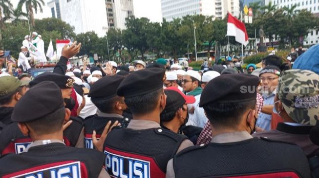 Polisi menghalau massa PA 212 yang berusaha menuju Istana Negara dan aksi saling dorong kedua belah pihak pun tak terhindarkan di kawasan Patung Kuda, Jakarta, Jumat (25/3/2022). [Suara.com/Yaumal Asri Adi Hutasuhut]
