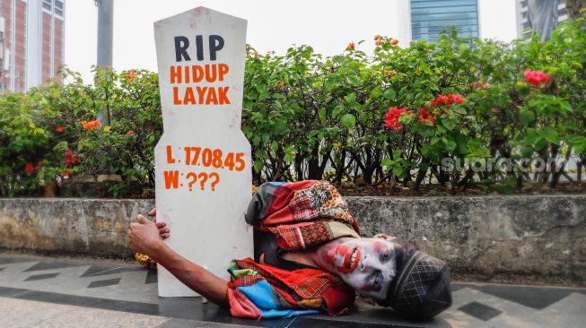 Seorang massa demonstrasi melakukan aksi teaterikal saat menggelar aksi darurat iklim di Jalan Sudirman, Jakarta Pusat, Jumat (25/3/2022). [Suara.com/Alfian Winanto]