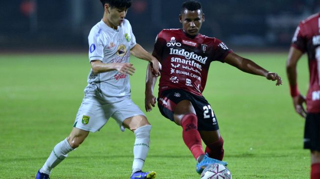 Pesepak bola Bali United Eber Bessa (kanan) berebut bola dengan pesepak bola Persebaya Surabaya Taisei Marukawa (kiri) saat pertandingan Liga 1 di Stadion I Gusti Ngurah Rai, Denpasar, Bali, Jumat (25/3/2022). [ANTARA FOTO/Fikri Yusuf/rwa]
