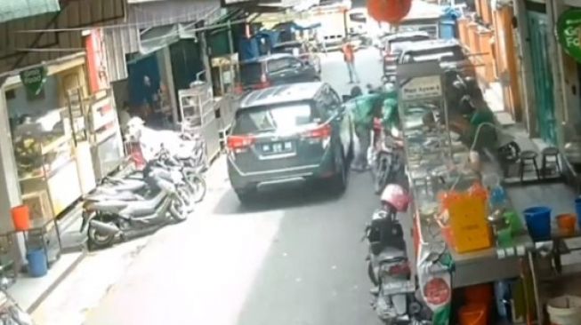 Tangkapan layar CCTV adu jotos driver ojol dengan pengendara mobil di Jalan Selat Panjang, Medan, Sumatera Utara, Jumat (25/3/2022). [Instagram@terangmedia]