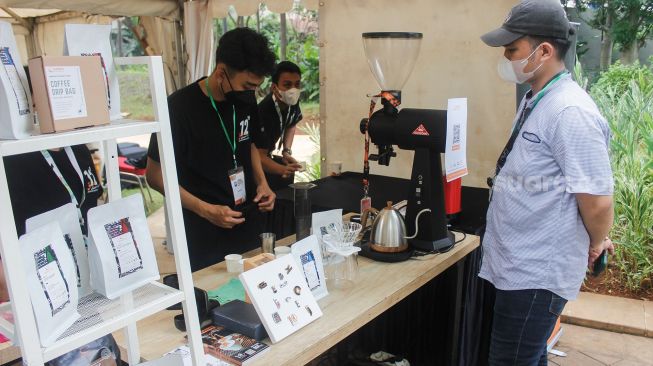 Pengunjung melihat-lihat berbagai jenis kopi saat Event Jakarta Coffee Experience 2022 di Grange Park Cipete, Jakarta Selatan, Jumat (25/3/2022). [Suara.com/Septian]