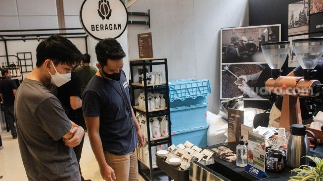 Pengunjung melihat-lihat berbagai jenis kopi saat Event Jakarta Coffee Experience 2022 di Grange Park Cipete, Jakarta Selatan, Jumat (25/3/2022). [Suara.com/Septian]