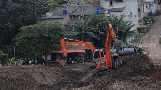 Pekerja menggunakan alat berat mengeruk lahan yang akan dijadikan Waduk Brigif, Jagakarsa, Jakarta, Minggu (27/3/2022). [Suara.com/Angga Budhiyanto]