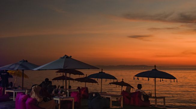 Pengunjung menikmati pemandangan matahari terbenam di pantai Tanjung Bias, Desa Senteluk, Kecamatan Batulayar, Lombok Barat, NTB, Sabtu (26/3/2022). ANTARA FOTO/Ahmad Subaidi