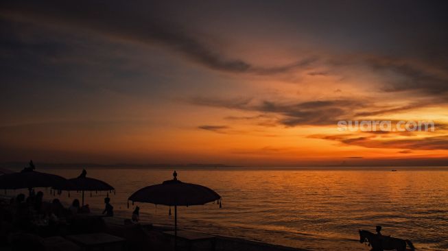 Pengunjung menikmati pemandangan matahari terbenam di pantai Tanjung Bias, Desa Senteluk, Kecamatan Batulayar, Lombok Barat, NTB, Sabtu (26/3/2022). ANTARA FOTO/Ahmad Subaidi