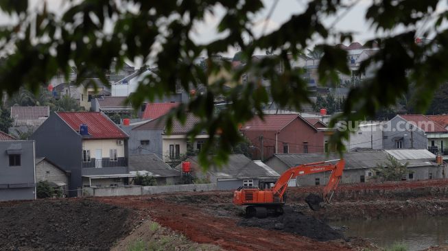 Pekerja menggunakan alat berat mengeruk lahan yang akan dijadikan Waduk Brigif, Jagakarsa, Jakarta, Minggu (27/3/2022). [Suara.com/Angga Budhiyanto]