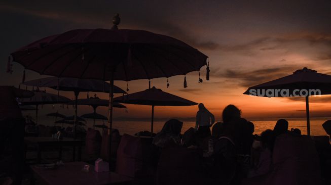 Pengunjung menikmati pemandangan matahari terbenam di pantai Tanjung Bias, Desa Senteluk, Kecamatan Batulayar, Lombok Barat, NTB, Sabtu (26/3/2022). ANTARA FOTO/Ahmad Subaidi