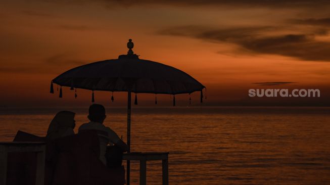 Pengunjung menikmati pemandangan matahari terbenam di pantai Tanjung Bias, Desa Senteluk, Kecamatan Batulayar, Lombok Barat, NTB, Sabtu (26/3/2022). ANTARA FOTO/Ahmad Subaidi