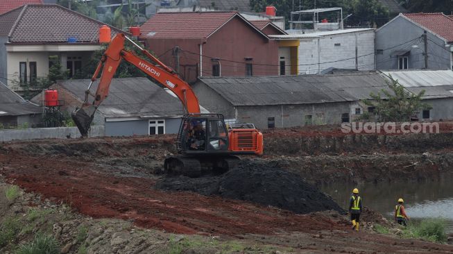 Pekerja menggunakan alat berat mengeruk lahan yang akan dijadikan Waduk Brigif, Jagakarsa, Jakarta, Minggu (27/3/2022). [Suara.com/Angga Budhiyanto]